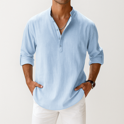 Men's light blue linen popover Henley shirt with band collar, rolled sleeves, and partial button placket, styled with white pants.