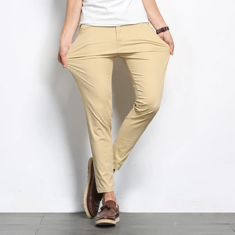 Men's beige slim fit cotton chino pants styled with white t-shirt and brown leather loafers