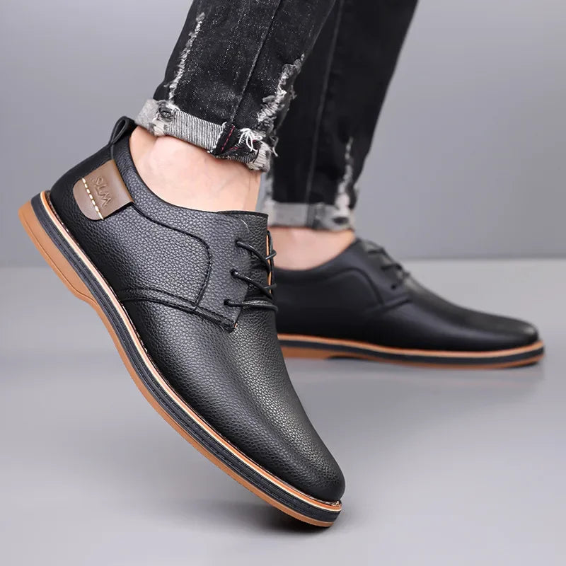 Black men's leather lace-up derby shoes with tan sole, worn with distressed black jeans, side and front view.