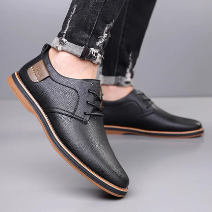 Black men's leather lace-up derby shoes with tan sole, worn with distressed black jeans, side and front view.