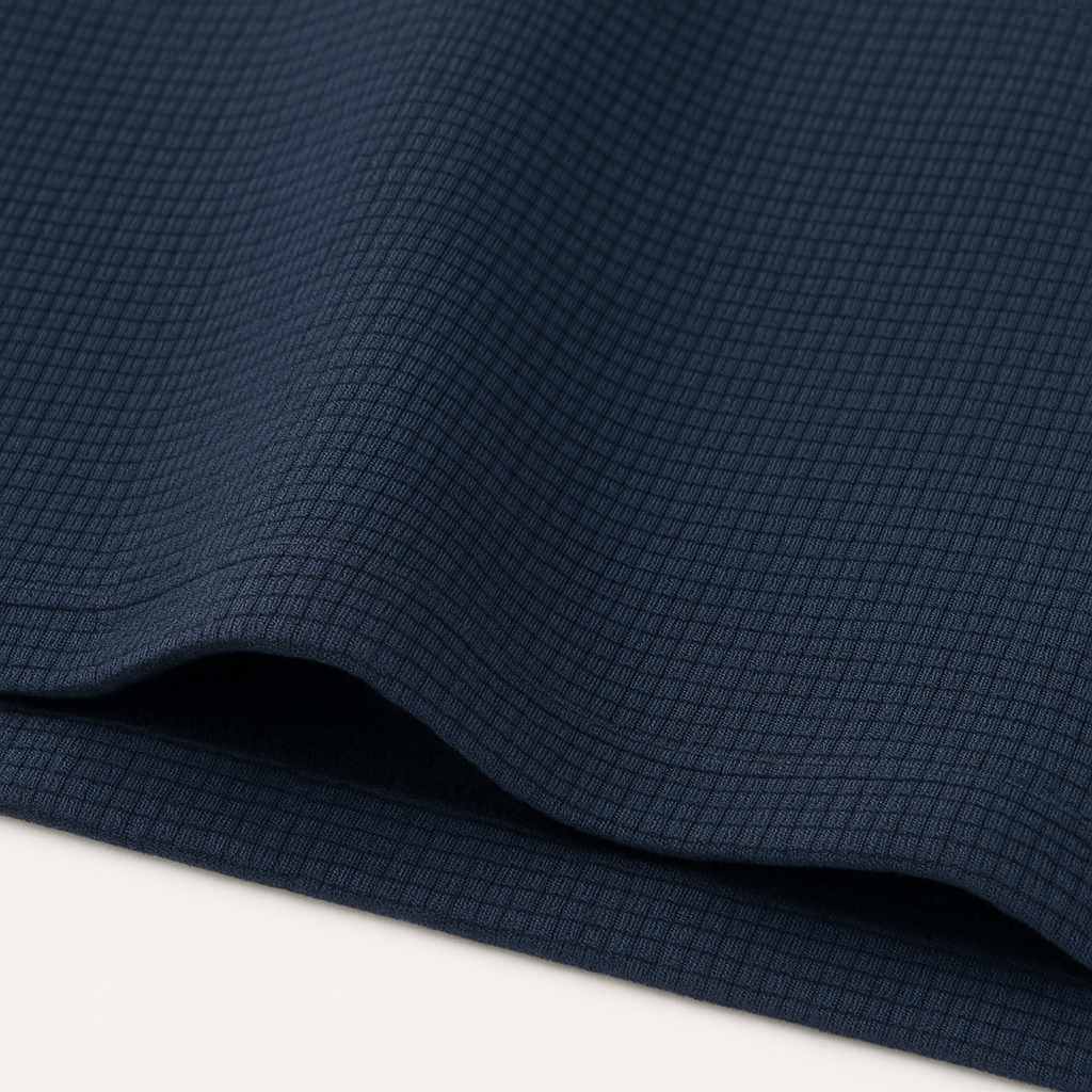 Navy blue waffle knit crewneck t-shirt fabric close-up showing textured grid pattern with soft drape and folds.