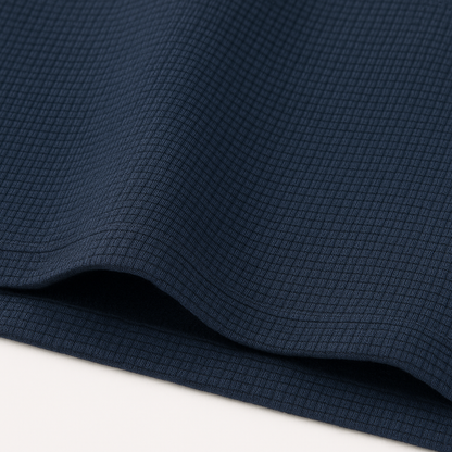 Navy blue waffle knit crewneck t-shirt fabric close-up showing textured grid pattern with soft drape and folds.