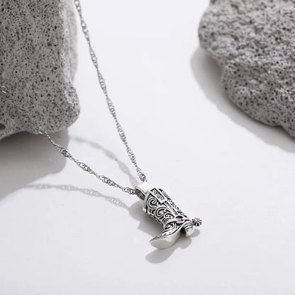 Silver necklace with ornate western cowboy boot charm pendant featuring intricate scrollwork and crystal details on twisted chain