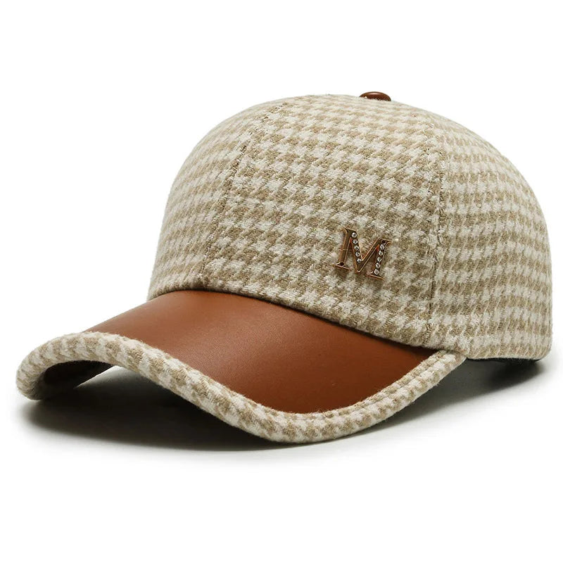 Beige houndstooth baseball cap with brown leather brim and gold rhinestone M logo emblem