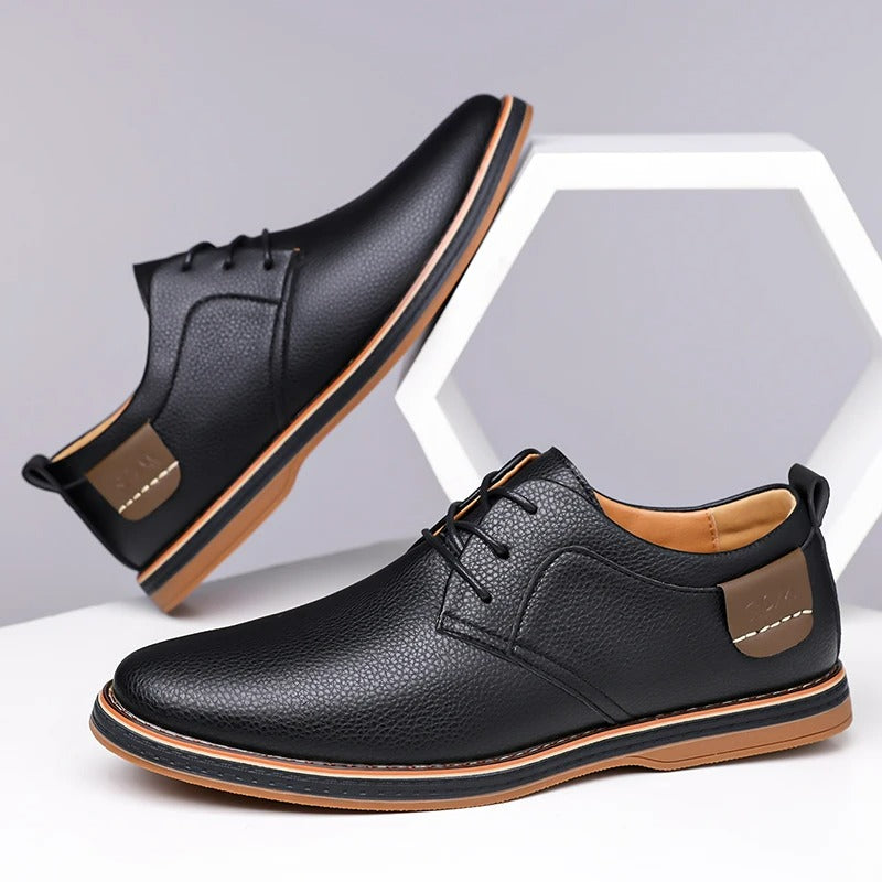 Black men's leather lace-up derby shoes with tan sole, pebbled texture, and brown heel tab accent, shown from two angles.