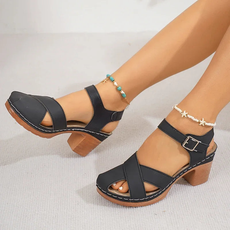Black block heel platform sandals with crisscross straps and ankle buckle closure, styled with beaded anklets