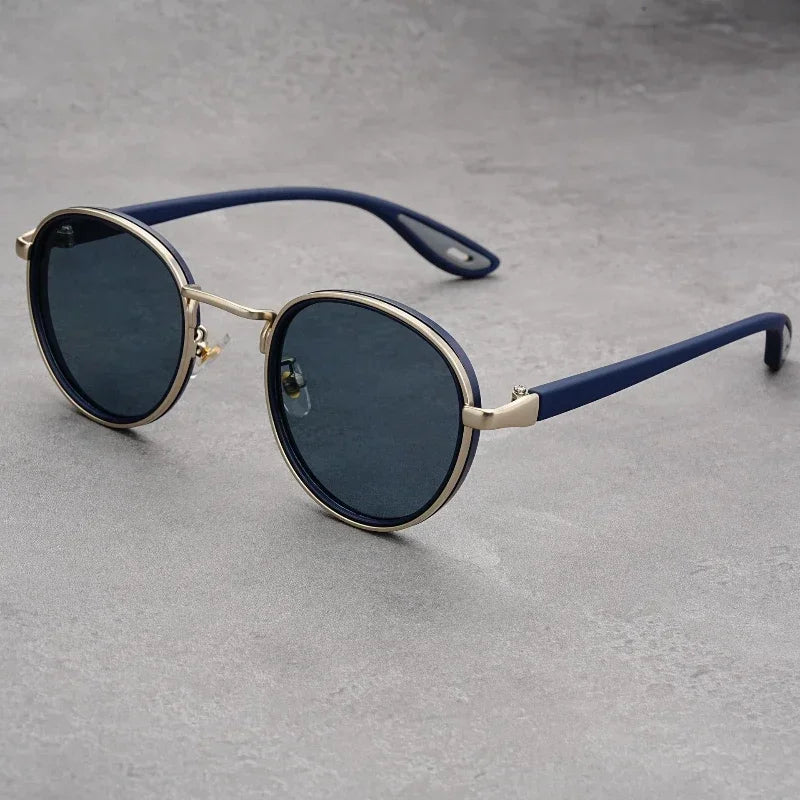 Round blue and gold UV400 sunglasses with dark lenses, metal frame, and navy blue temples on gray surface.