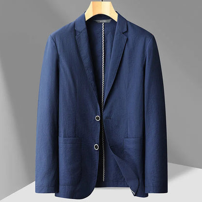 Navy blue men's two-button blazer on wooden hanger with notch lapel and patch pockets, displayed on gray background