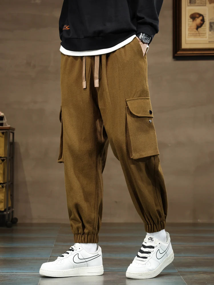 Men's brown cargo joggers with side pockets, elastic cuffs, drawstring waist, paired with white Nike Air Force 1 sneakers.