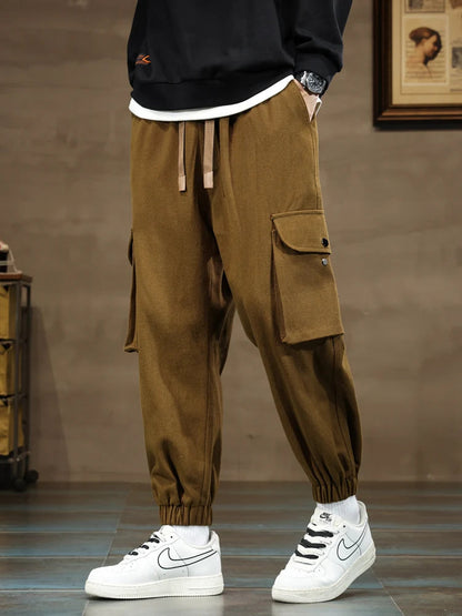 Men's brown cargo joggers with side pockets, elastic cuffs, drawstring waist, paired with white Nike Air Force 1 sneakers.