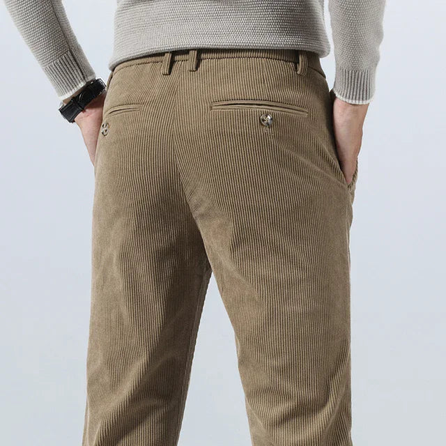 Men's khaki corduroy slim fit pants shown from the back, featuring a rear welt pocket and belt loops.