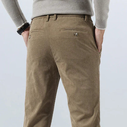 Men's khaki corduroy slim fit pants shown from the back, featuring a rear welt pocket and belt loops.