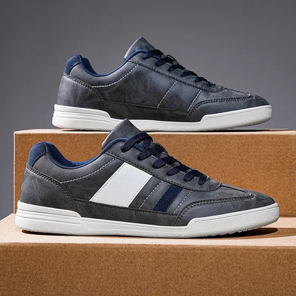 Gray men's Viero low-top sneakers with navy blue laces, white stripe accent, and white sole, displayed on cardboard boxes.