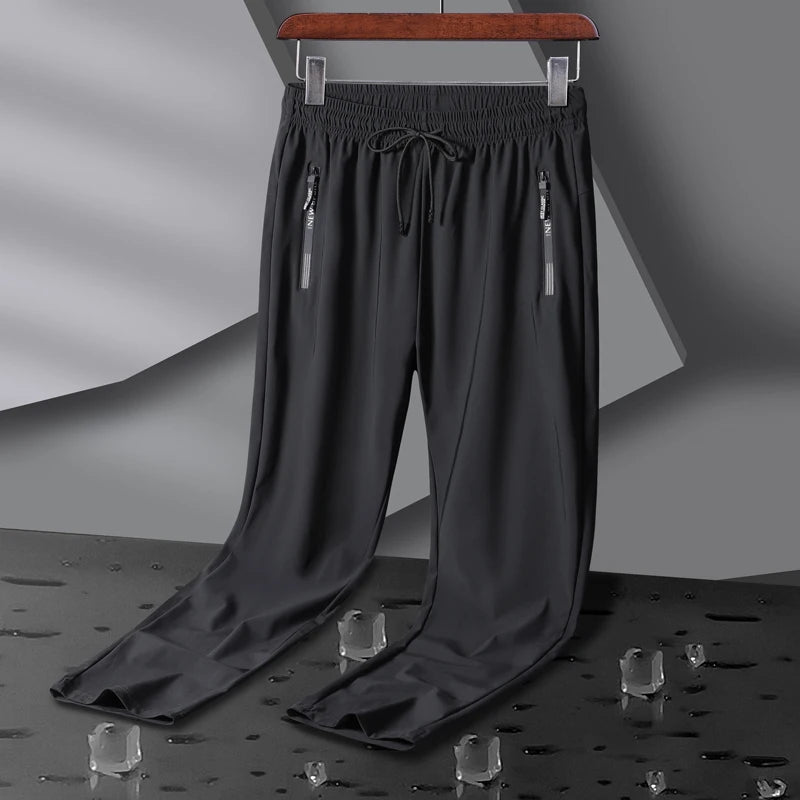 Dark gray men's stretch sweatpants with elastic waistband, drawstring, and dual silver zip pockets on hanger
