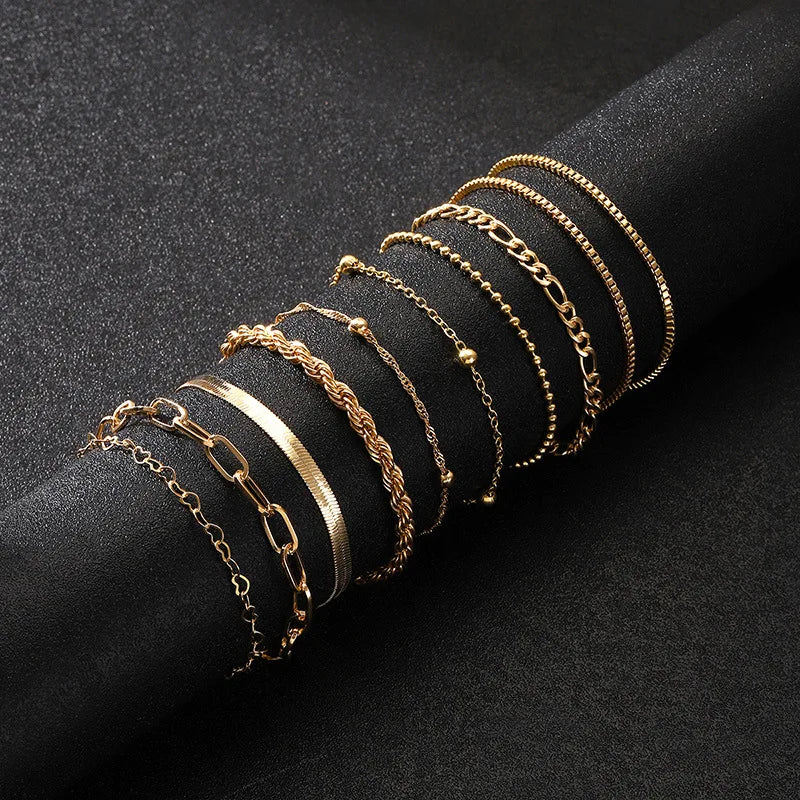 Gold chain bracelet set with 8 styles including paperclip, rope, snake, beaded, Figaro, and box chains on black display.