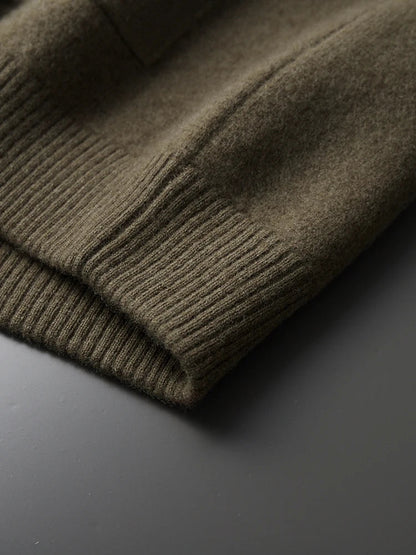 Close-up of olive green merino wool cardigan jacket cuff showing ribbed knit trim detail on gray surface