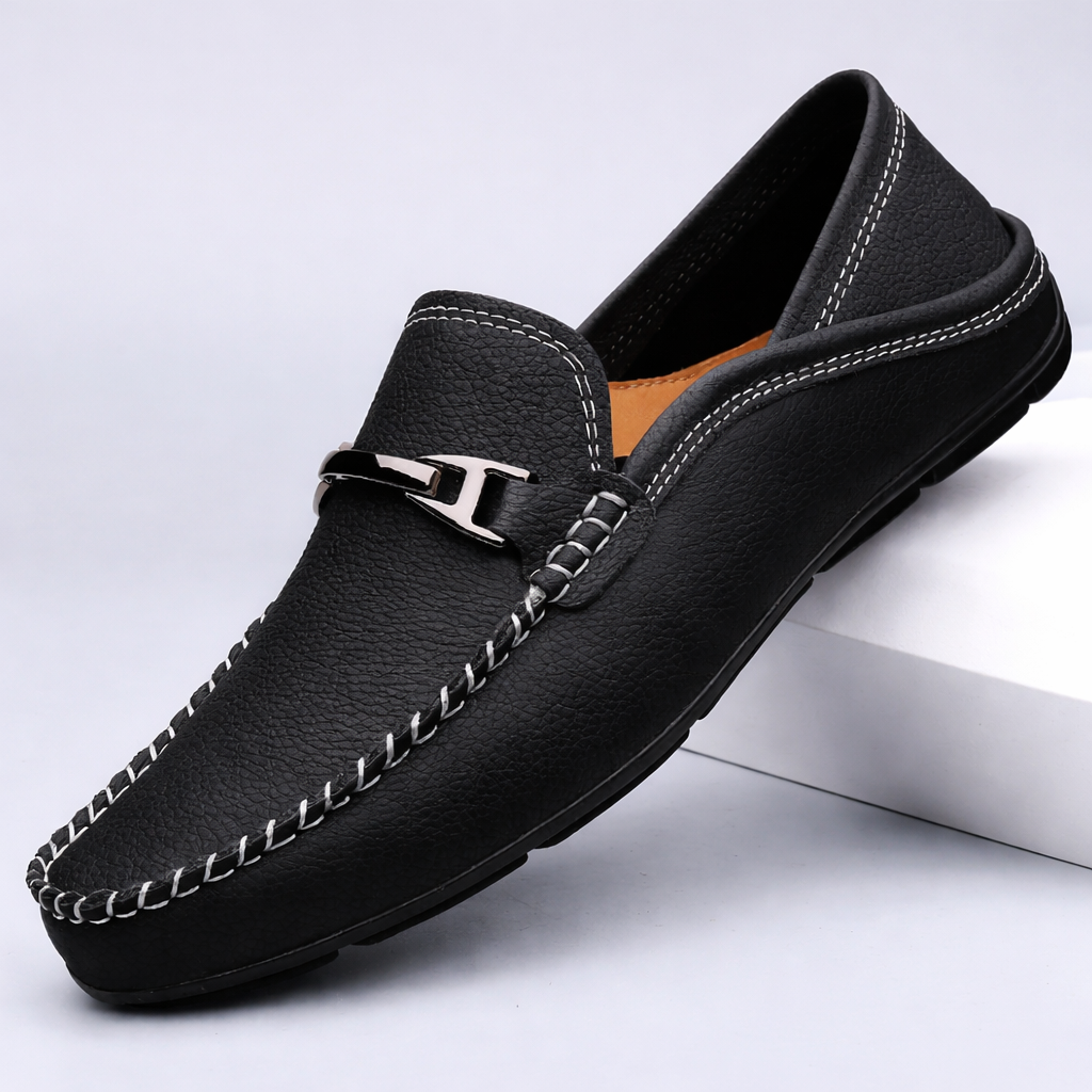 Black leather men's slip-on loafer with white contrast stitching, metal horsebit buckle, and tan interior lining.