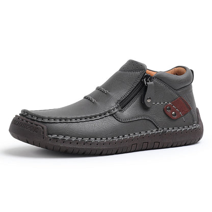 Gray men's leather slip-on ankle boots with side zipper, hand stitching, brown accent patch, and rubber sole.