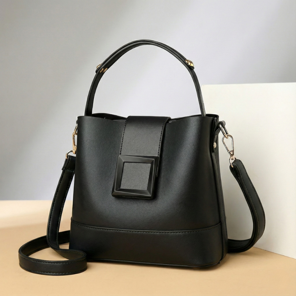 Black leather bucket handbag with top handle, adjustable crossbody strap, square buckle detail, and gold hardware accents.