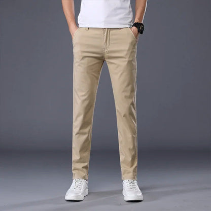 Men's slim fit khaki chino dress pants with white sneakers and t-shirt on gray background