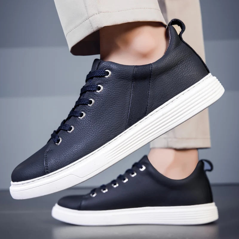 Navy and black leather lace-up low-top men's sneakers with white platform soles, shown on model wearing khaki pants