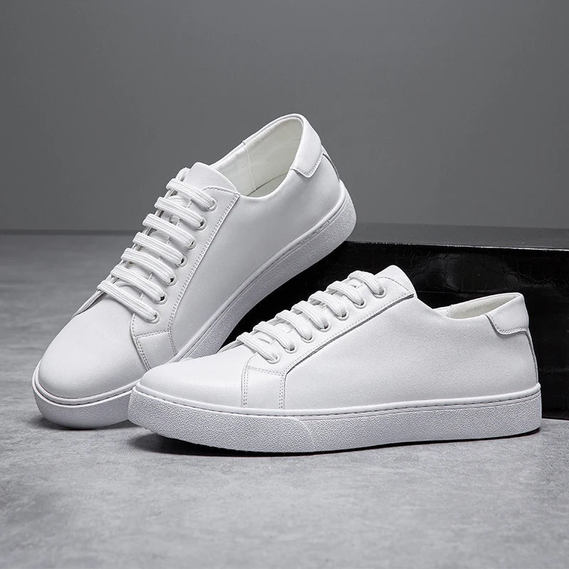 White leather lace-up sneakers for men with flat sole, displayed in pairs against gray background and black box