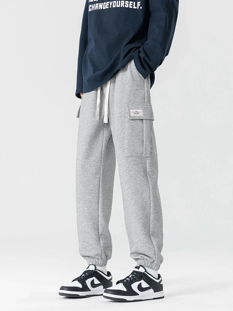 Men's gray cargo joggers with drawstring waist, side pockets, and elastic cuffs worn with sneakers