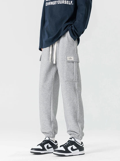 Men's gray cargo joggers with drawstring waist, side pockets, and elastic cuffs worn with sneakers