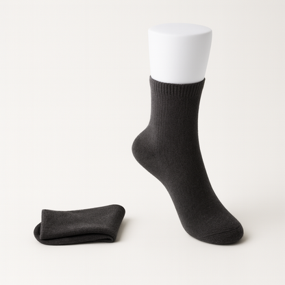 Dark charcoal women's cashmere comfort ankle socks displayed on a mannequin foot with a folded pair beside it.