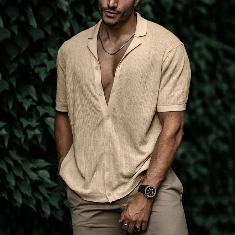 Man wearing a beige short sleeve button-down knit shirt with open collar, paired with khaki pants and a watch.