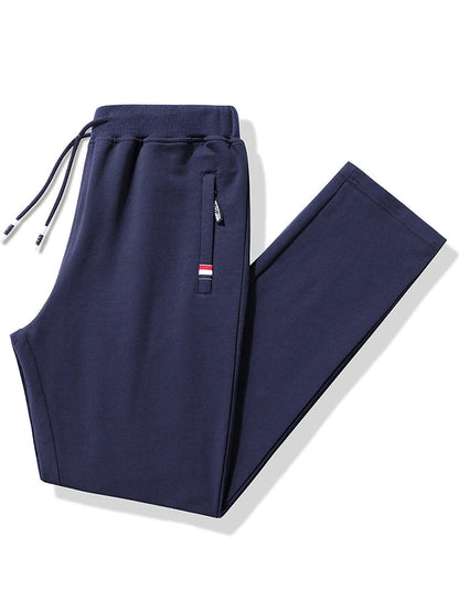 Navy blue men's cotton drawstring sweatpants with elastic waistband, zippered pocket, and red stripe accent detail.