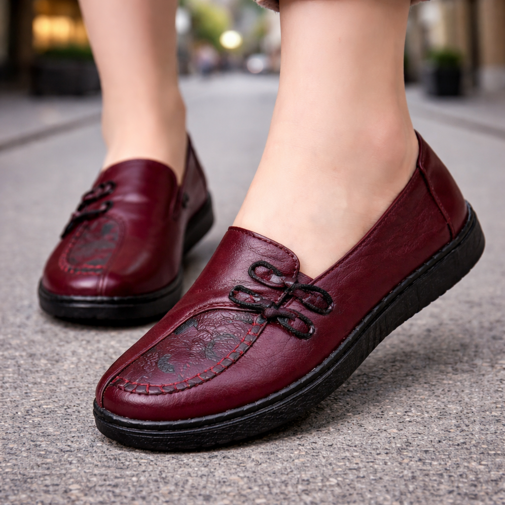Burgundy leather women's slip-on loafers with decorative black knotted detail and contrast stitching on black sole