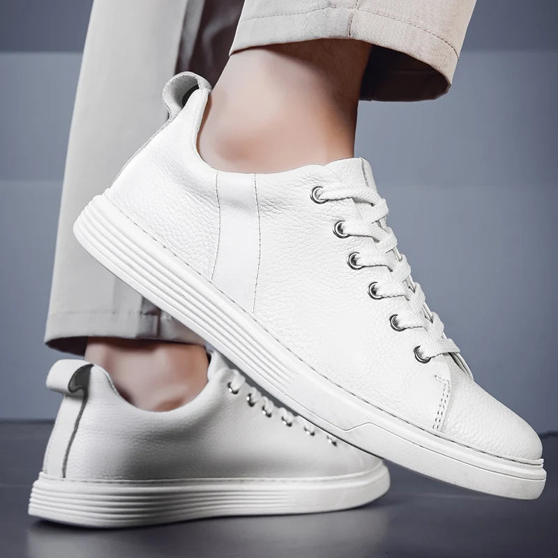 White leather lace-up low-top men's sneakers with silver eyelets and textured sole, styled with beige trousers