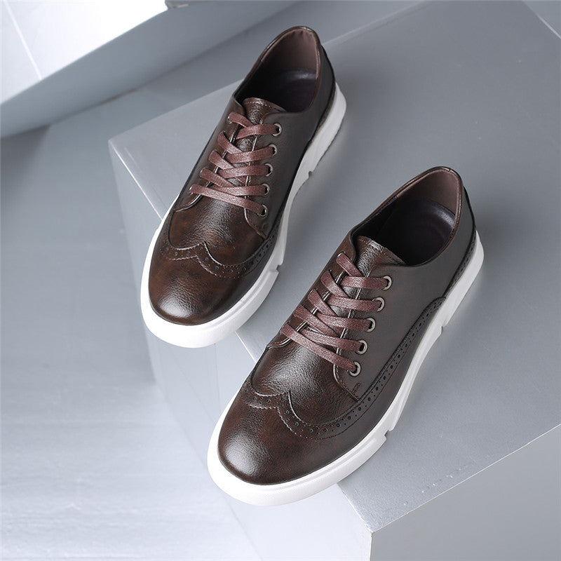Brown leather brogue lace-up sneakers for men with white platform sole and decorative perforations, displayed on gray blocks