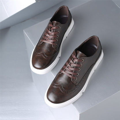 Brown leather brogue lace-up sneakers for men with white platform sole and decorative perforations, displayed on gray blocks