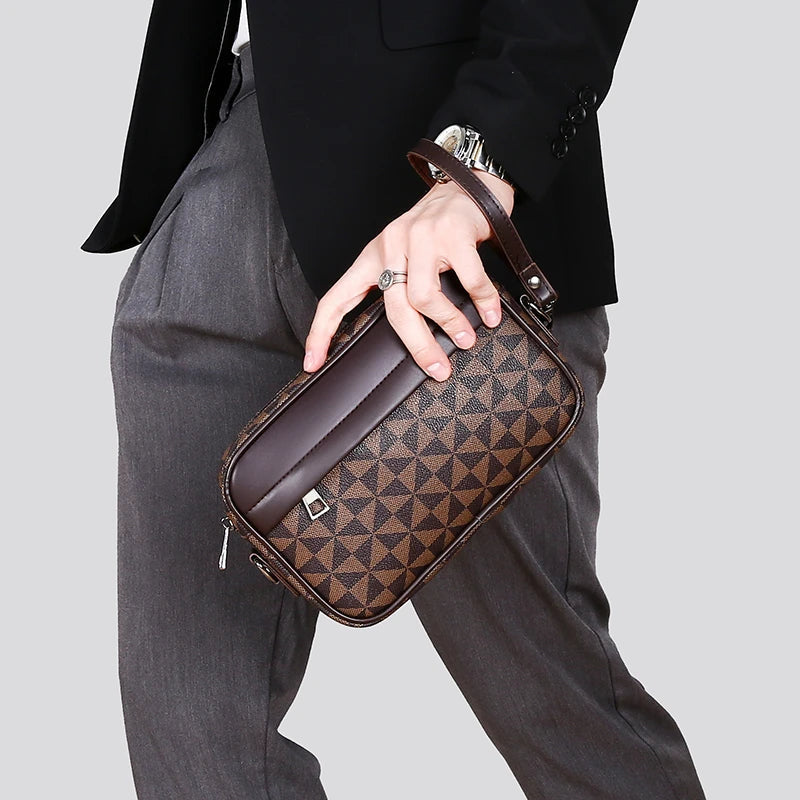Brown checkered crossbody bag with adjustable strap held by person in gray pants and black jacket