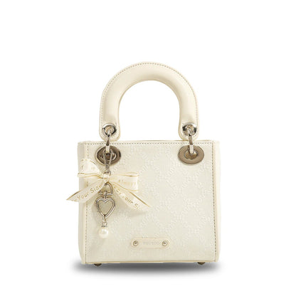 Cream jacquard mini handbag with gold hardware, heart charm, pearl accent, satin bow, and structured top handle