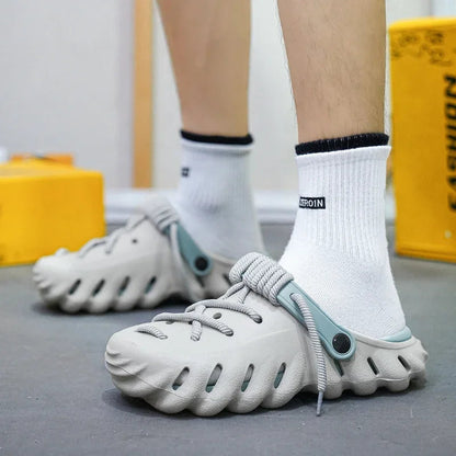 Men wearing gray cushioned foam lace-up clog shoes with white socks, featuring ventilation holes and teal accents.