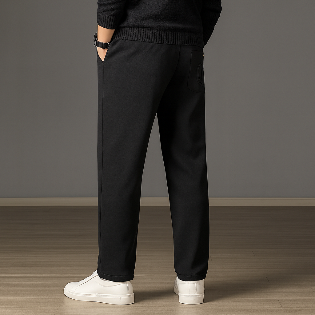 Man wearing black ice silk drawstring sweatpants with elastic waistband, paired with black sweater and white sneakers.