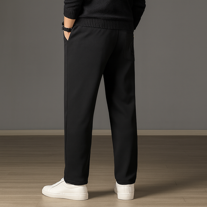 Man wearing black ice silk drawstring sweatpants with elastic waistband, paired with black sweater and white sneakers.