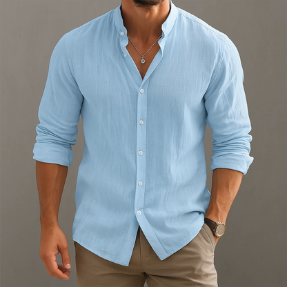 Man wearing a light blue linen band collar button-up shirt with long sleeves, paired with khaki pants and a watch.