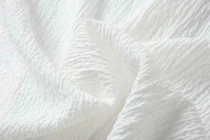 Close-up of white crinkled cotton linen fabric texture showing soft wrinkled surface detail for men's shirt and pants set