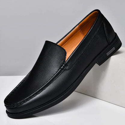 Black men's leather slip-on loafers with contrast stitching, tan interior lining, and low heel on white surface