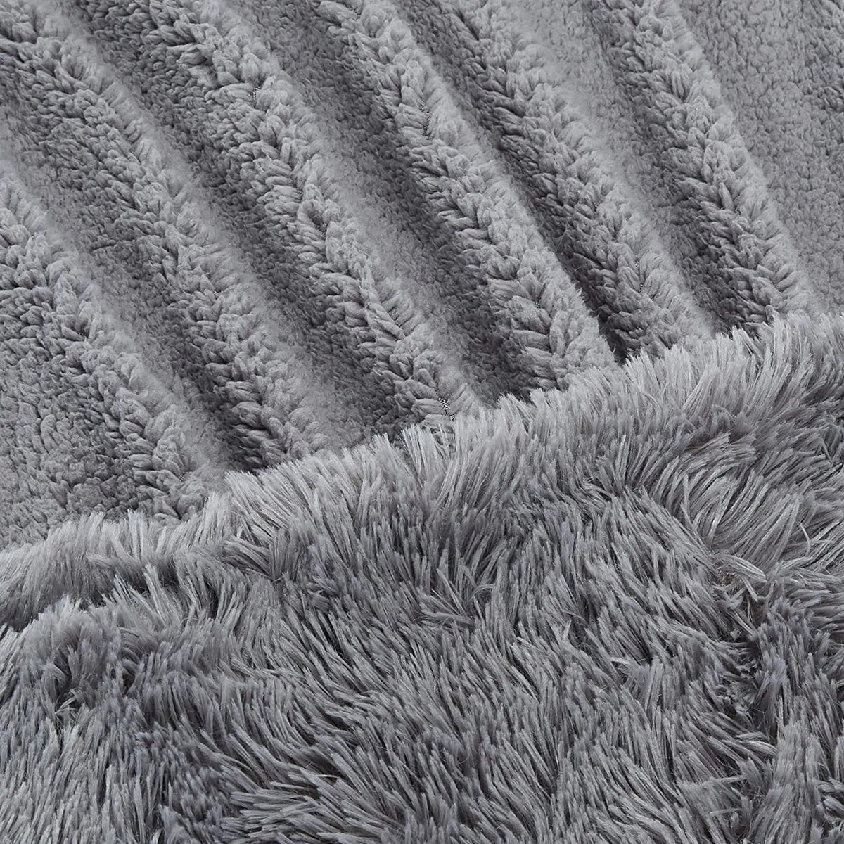Gray faux fur plush throw blanket with diagonal ribbed texture pattern and long shaggy fringe edge detail.