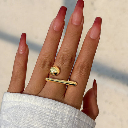 Gold-tone adjustable open bar and ball ring on woman's hand with red ombre manicure nails