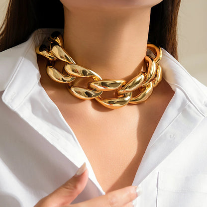 Chunky oversized gold Cuban link chain choker necklace worn on woman in white shirt, bold statement jewelry