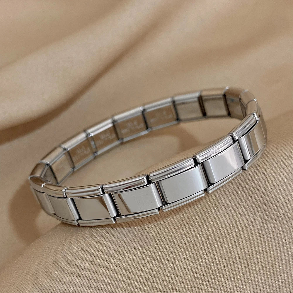 Silver interlocking rectangular link chain bracelet displayed on beige fabric background