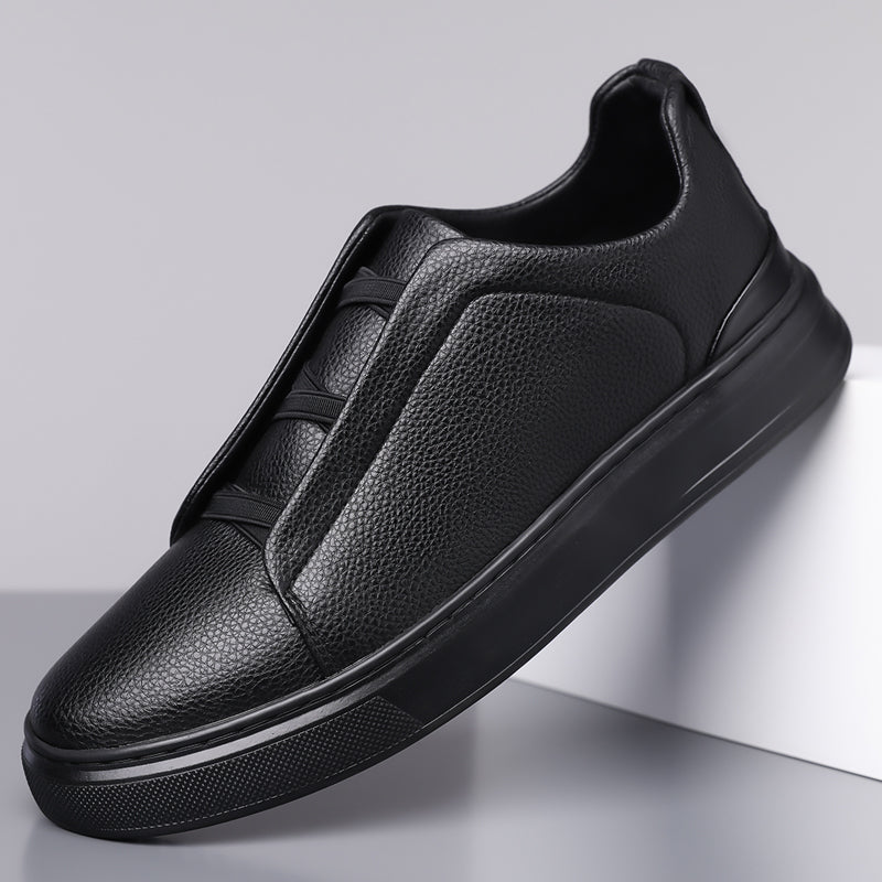 Black men's leather slip-on sneakers with elastic lacing, pebbled texture upper, contrast trim, and thick black sole.