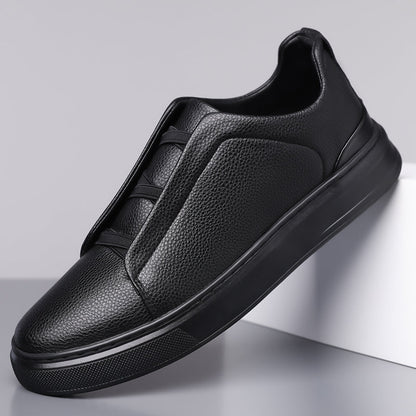 Black men's leather slip-on sneakers with elastic lacing, pebbled texture upper, contrast trim, and thick black sole.