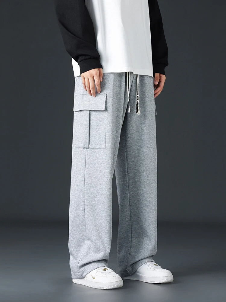 Men's wide-leg gray cargo sweatpants with large side pockets and drawstring waist, styled with white sneakers.